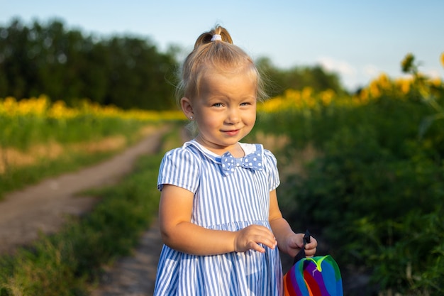 Bambina che tiene un aquilone su un campo di girasoli.