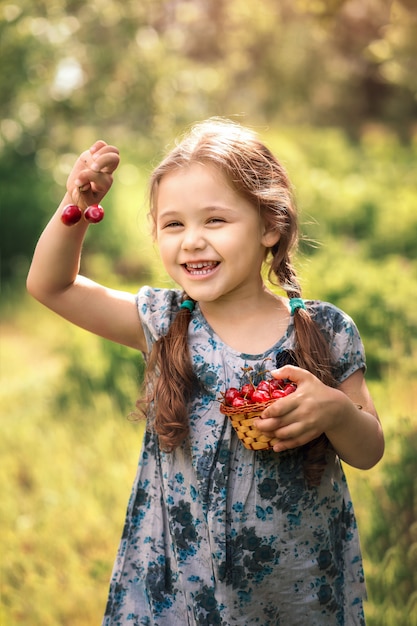 bambina che tiene un cestino delle ciliege sulla natura in estate