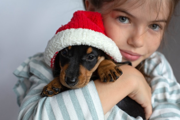 Bambina che tiene un cucciolo di bassotto nel suo regalo di Capodanno per animali da compagnia