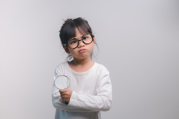 Bambina che tiene una lente d'ingrandimento su sfondo bianco