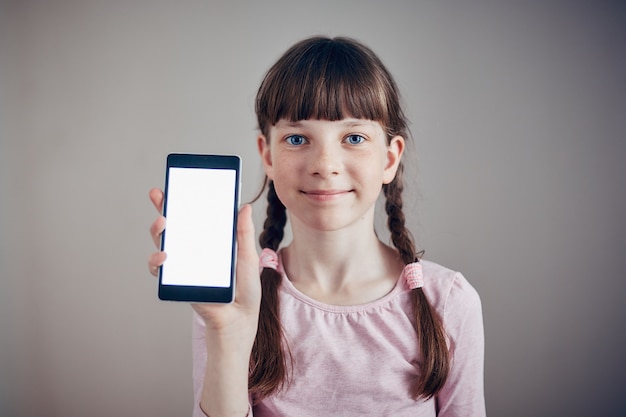 Bambina che tiene uno smartphone con uno schermo bianco