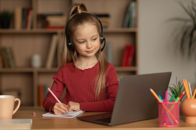 Bambina che usa il computer portatile che ha l'apprendimento di classe a distanza a casa