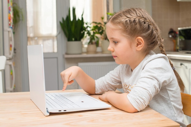 Bambina che usa il laptop a casa Bambino che guarda video o gioca sul notebook