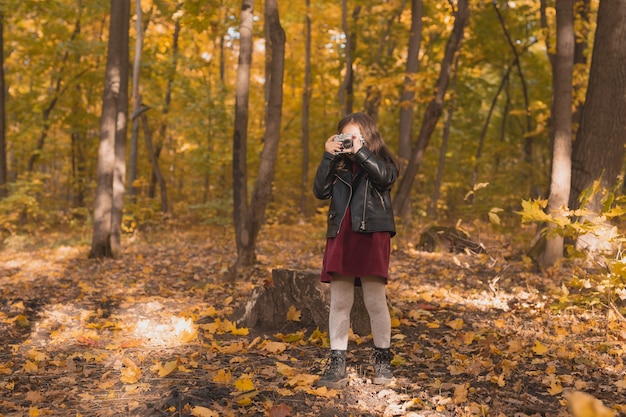 Bambina che usa una macchina fotografica antiquata nella stagione autunnale del fotografo naturalista e nel tempo libero