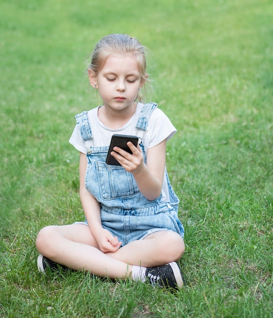 Bambina che usa uno smartphone nel parco