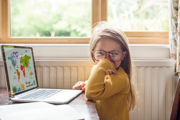 Bambina che usando il concetto di e-learning del computer portatile di Digital