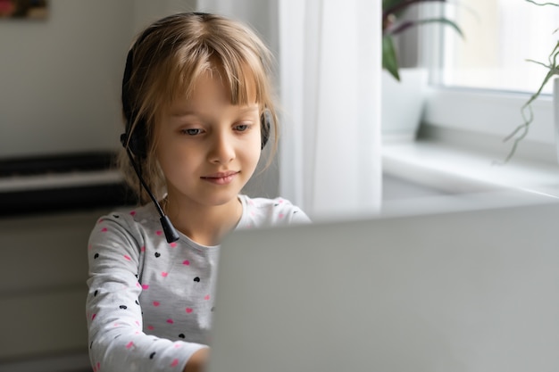 Bambina che utilizza la chat video sul portatile a casa. Spazio per il testo