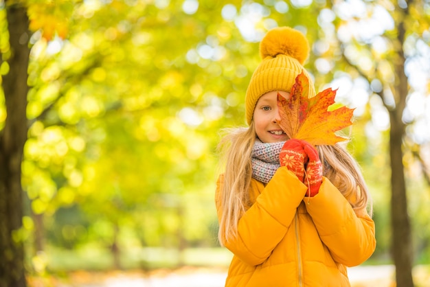 Bambina con capelli biondi in autunno in abiti gialli