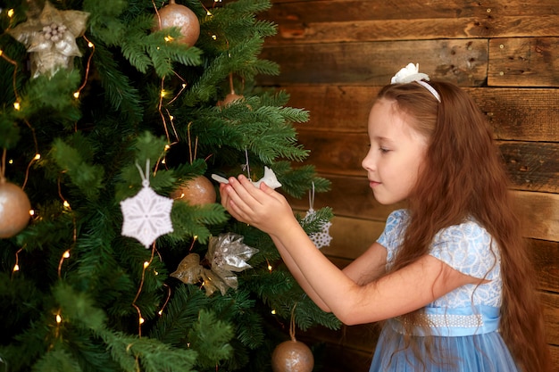 Bambina con capelli lunghi che decorano l'albero di Natale