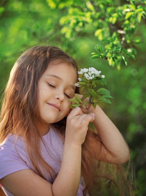 Bambina con capelli lunghi vicino ad un albero di fioritura in natura