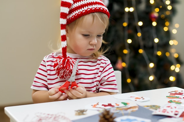Bambina con cappello di Natale che fa decorazioni per Natale Creatività per bambini e artigianato natalizio