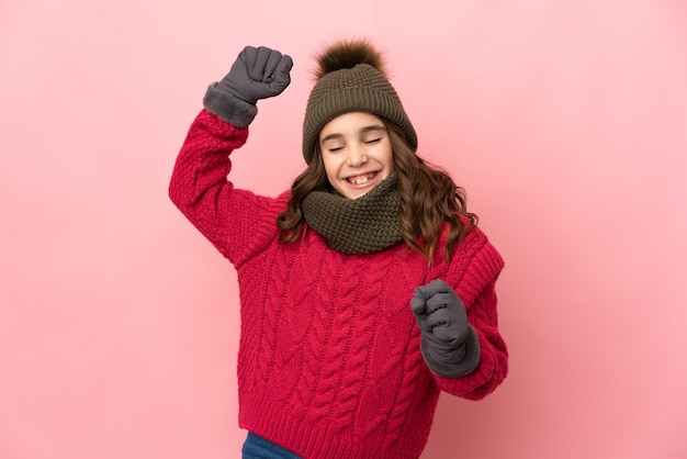 Bambina con cappello invernale isolato che celebra una vittoria