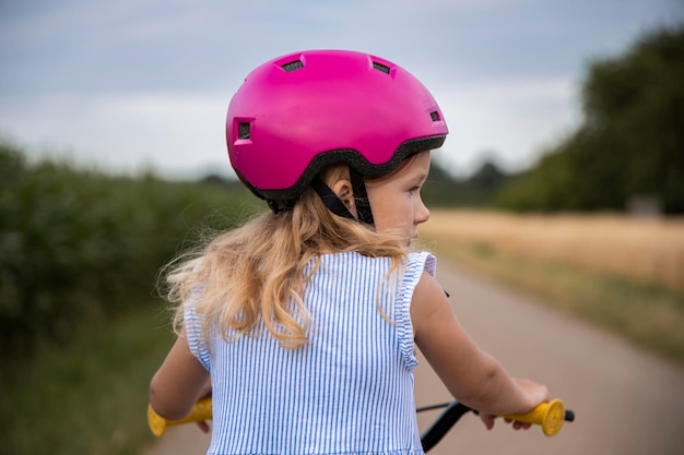 Bambina con casco che va in bicicletta sul campo