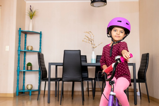 Bambina con casco da bicicletta felice di guidare la sua bici a casa