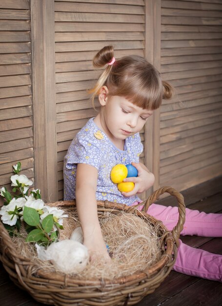 Bambina con cesto pieno di uova colorate