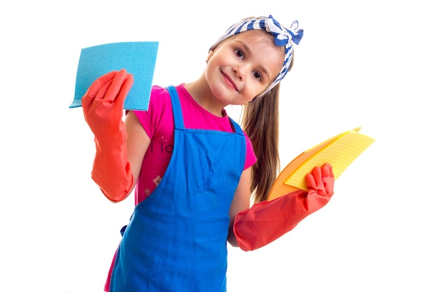 Bambina con coda di cavallo in camicia rosa e grembiule blu con guanti rossi che tengono spolverini colorati