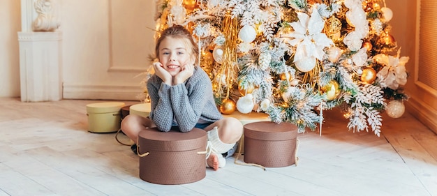 Bambina con confezione regalo vicino all'albero di Natale