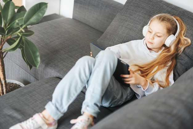 Bambina con cuffie e tablet a casa