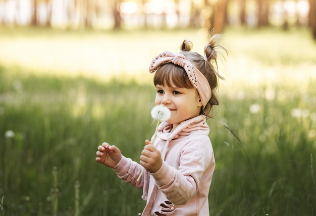 Bambina con dente di leone bianco nel parco in estate