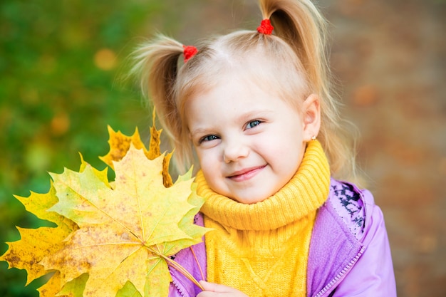 bambina con foglia gialla d'autunno nelle mani