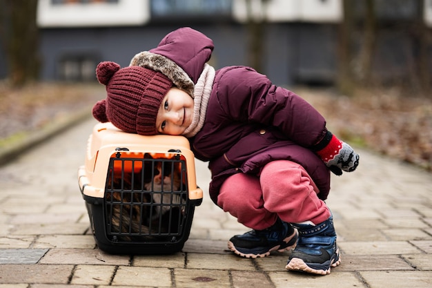 Bambina con gattino in viaggio gabbia di plastica carrozza all'aperto al parco