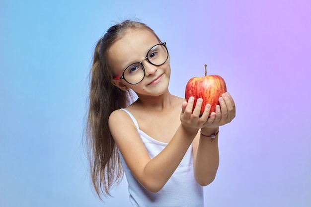 Bambina con gli occhiali, con in mano una mela rossa.