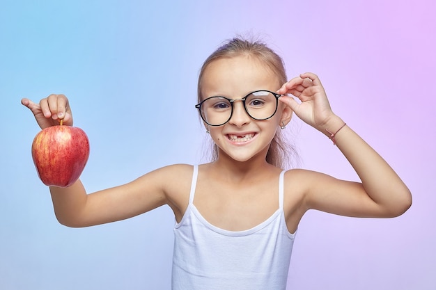 Bambina con gli occhiali, con in mano una mela rossa.