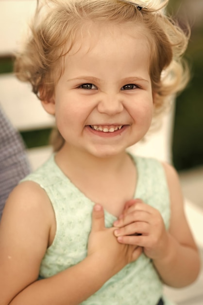 Bambina con i capelli biondi sorride in abito estivo