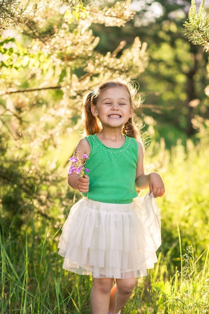 bambina con i capelli lunghi in un abito sulla natura in estate