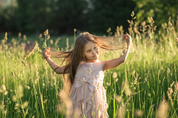 bambina con i capelli lunghi in un bellissimo abito sulla natura in estate