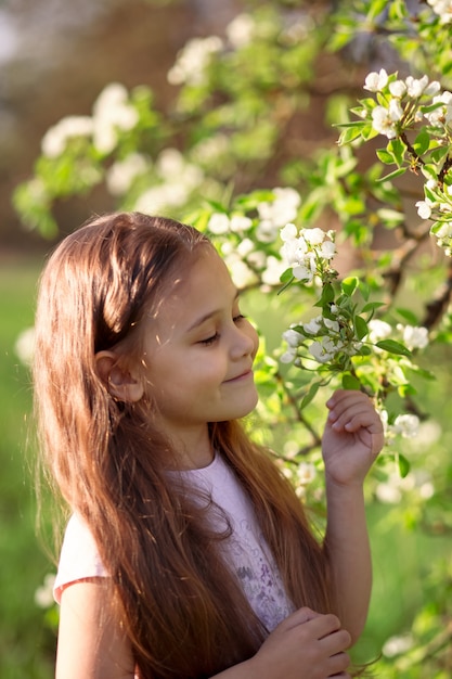 Bambina con i capelli lunghi vicino a un albero in fiore