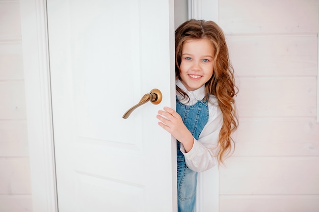 bambina con i capelli ricci fa capolino fuori dalla porta e sorride