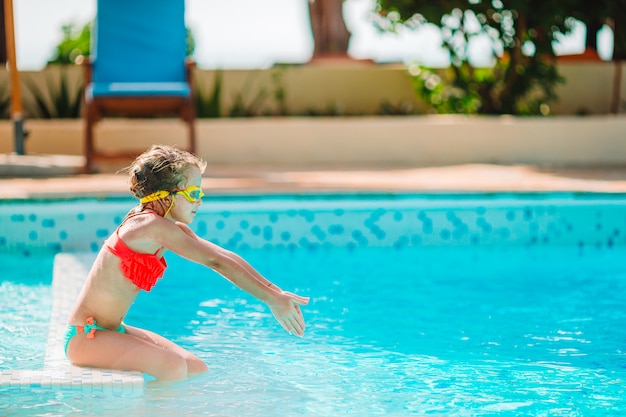 Bambina con il cerchio di gomma gonfiabile divertendosi nella piscina all'aperto in albergo di lusso