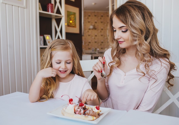 Bambina con la madre che mangia il gelato in un accogliente caffè. Buon rapporto di genitori e figli.