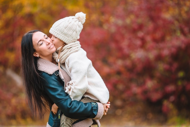 Bambina con la mamma nel parco al giorno di autunno