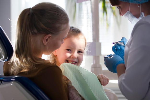 Bambina con la mamma sulla poltrona del dentista - il bambino sorride, primi piani