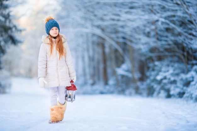 Bambina con latern nella foresta congelata alla vigilia di Natale