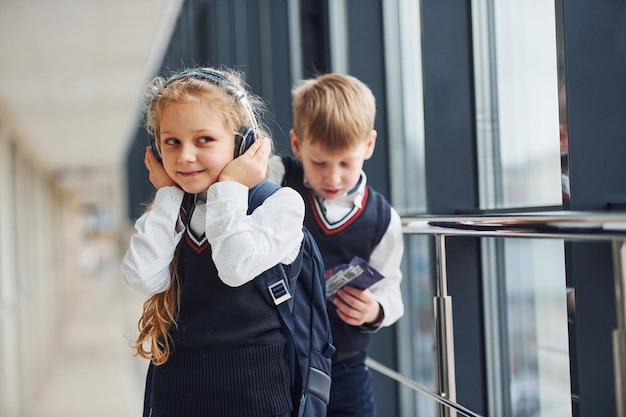 Bambina con le cuffie in uniforme che insieme al ragazzo in corridoio Concezione dell'istruzione