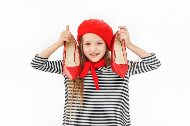 Bambina con le scarpe rosse in mano.