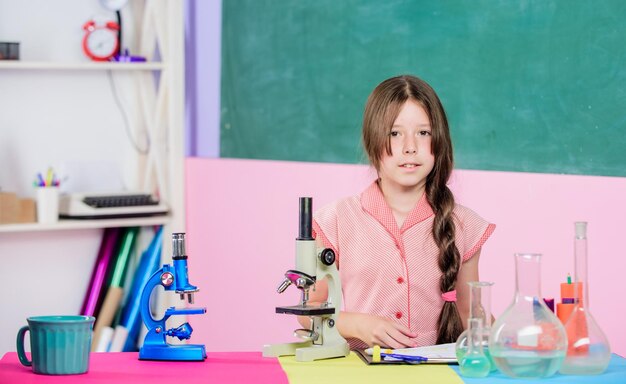 Bambina con microscopio Esperimento scientifico Lezione affascinante Esplora microbiologia Studia biologia Educazione biologica Ragazza lezione di biologia provette Lezione di scienza Laboratorio scolastico