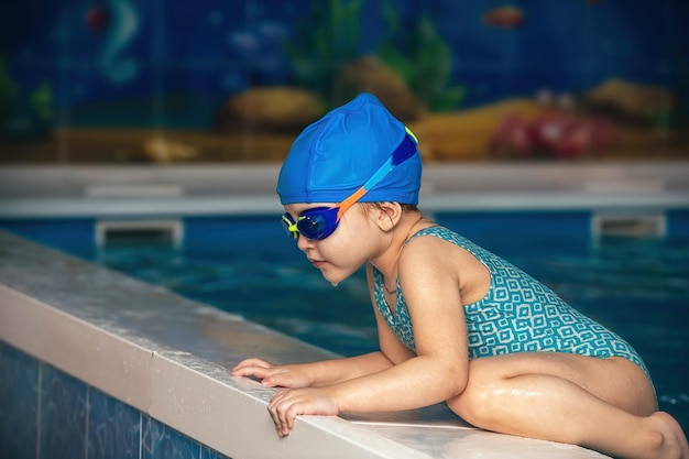 bambina con occhiali impermeabili e un costume da bagno a una lezione di nuoto in una piscina coperta