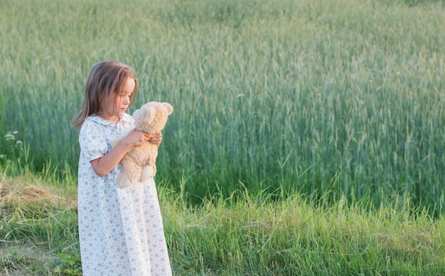 Bambina con orsacchiotto in campo