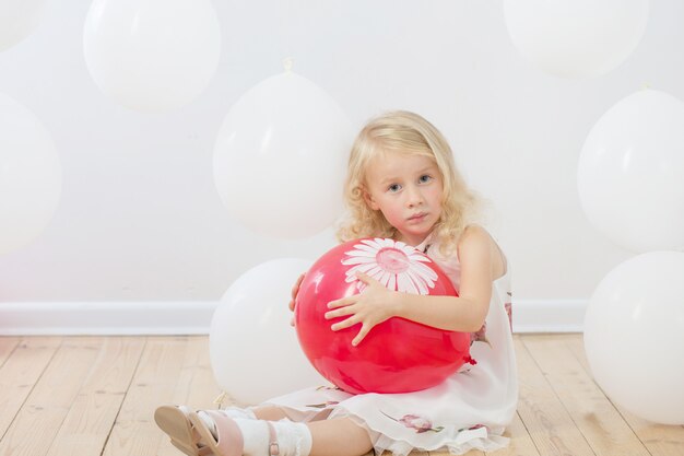 Bambina con palloncini bianchi e rossi al coperto