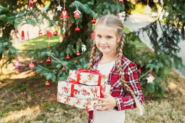 bambina con regali nei pressi di un albero di Natale,