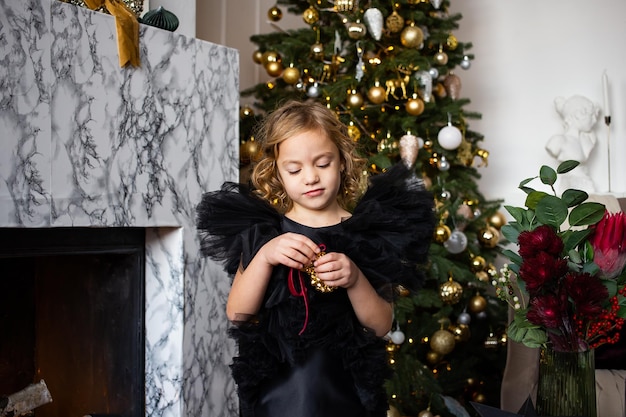 Bambina con regalo di Natale nelle sue mani vicino ad alberi di Natale con luci Buon Natale e buone feste