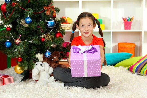 Bambina con scatola regalo vicino all'albero di Natale christmas