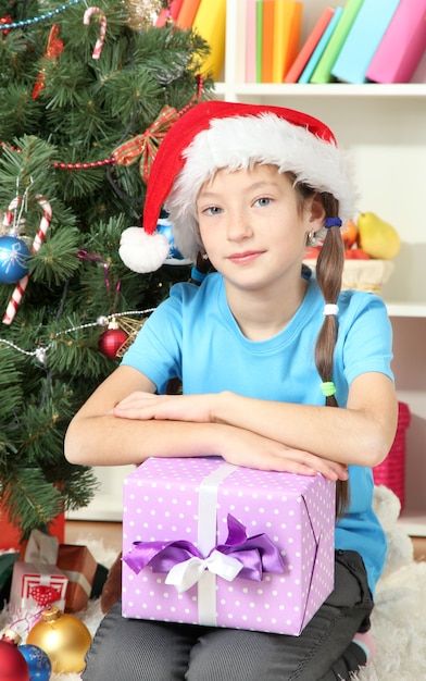 Bambina con scatola regalo vicino all'albero di Natale