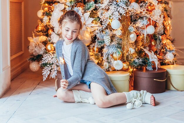 Bambina con sparkler vicino all'albero di Natale