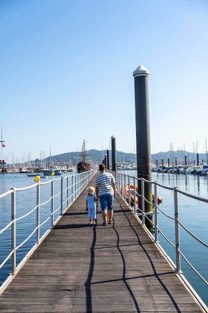 Bambina con suo padre che cammina lungo un molo di legno