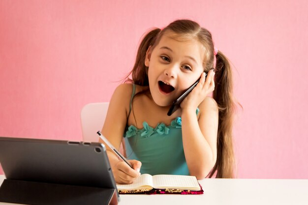 Bambina con telefono e tablet al tavolo